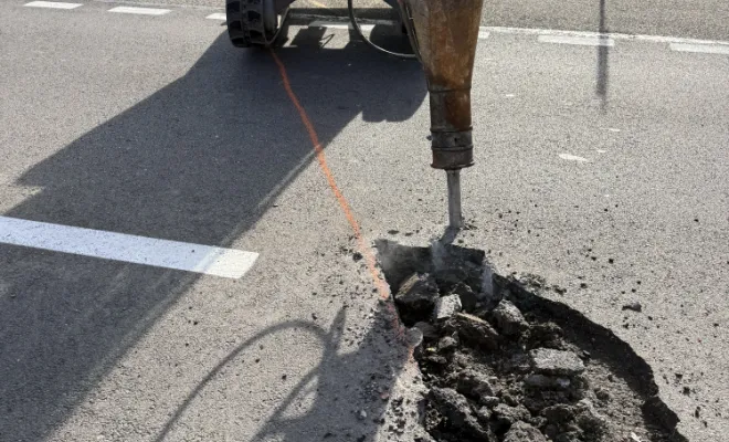 Réalisation d'une tranchée dans l'asphalte à l'aide d'un brise-roche pour le passage de la fibre optique.