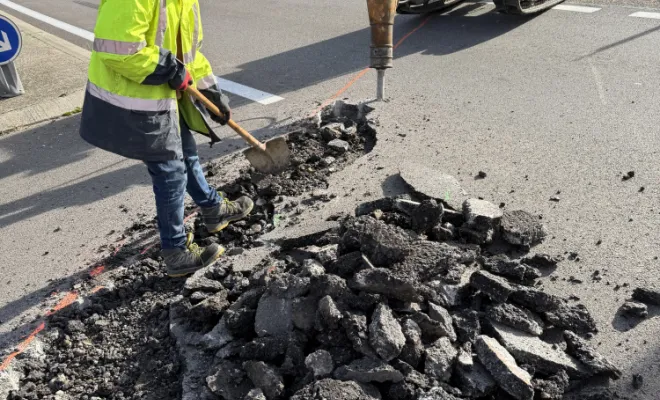 Chantier de travaux publics en cours avec une pelleteuse préparant le terrain pour des travaux de voirie.