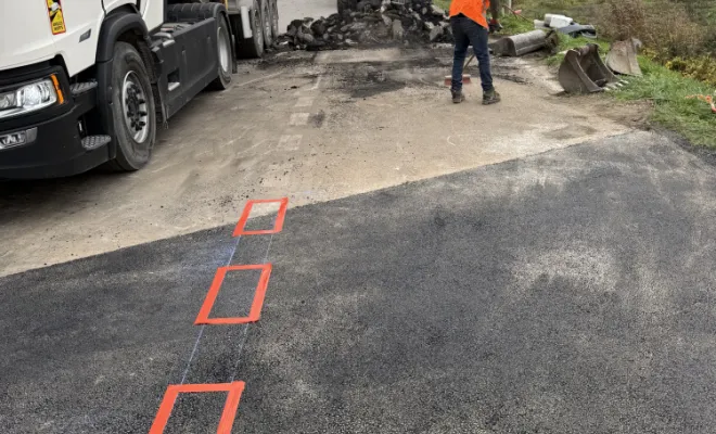 Équipe d'ouvriers en plein travail de terrassement et d'aménagement de chaussée sur un chantier de travaux publics.
